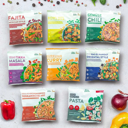 Acht verschiedene Live Fresh Fertiggerichte in bunten Verpackungen mit Gerichten wie Fajita Mexican Style. Vegan Tikka Masala. Kurkuma Curry. Gemüse Chili. Oriental Style und High Protein Pasta. Die Auswahl zeigt verschiedene gesunde Fertiggerichte mit viel Gemüse sowie veganen und proteinreichen Optionen.