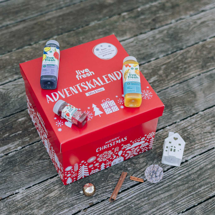 Adventskalender von LiveFresh in Rot mit Säften und Shots vor holzigem Hintergrund