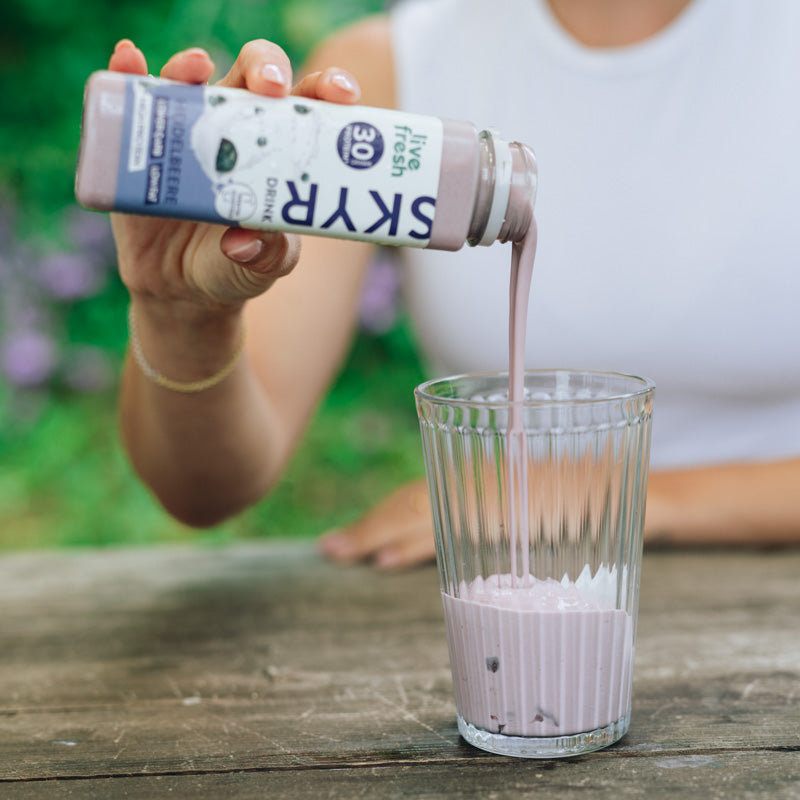 Skyr Drink Heidelbeere wird in ein Glas geschüttet. 