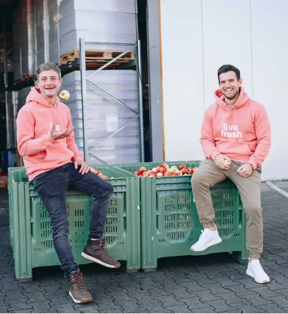 Die LiveFresh-Gründer Bene und Simon auf Apfelkisten vor der Produktion
